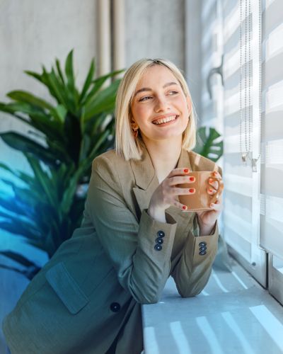 Frau an einem Fenster mit Fl&auml;chenvorh&auml;ngen